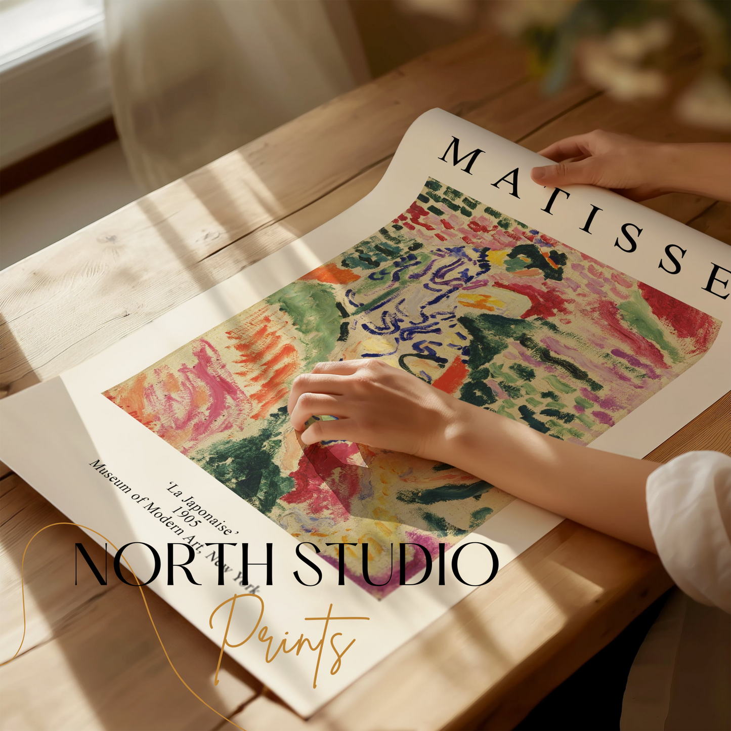 Hands unrolling a Matisse 'La Japonaise' art print on a wooden table, showcasing its vibrant abstract design and artistic details.