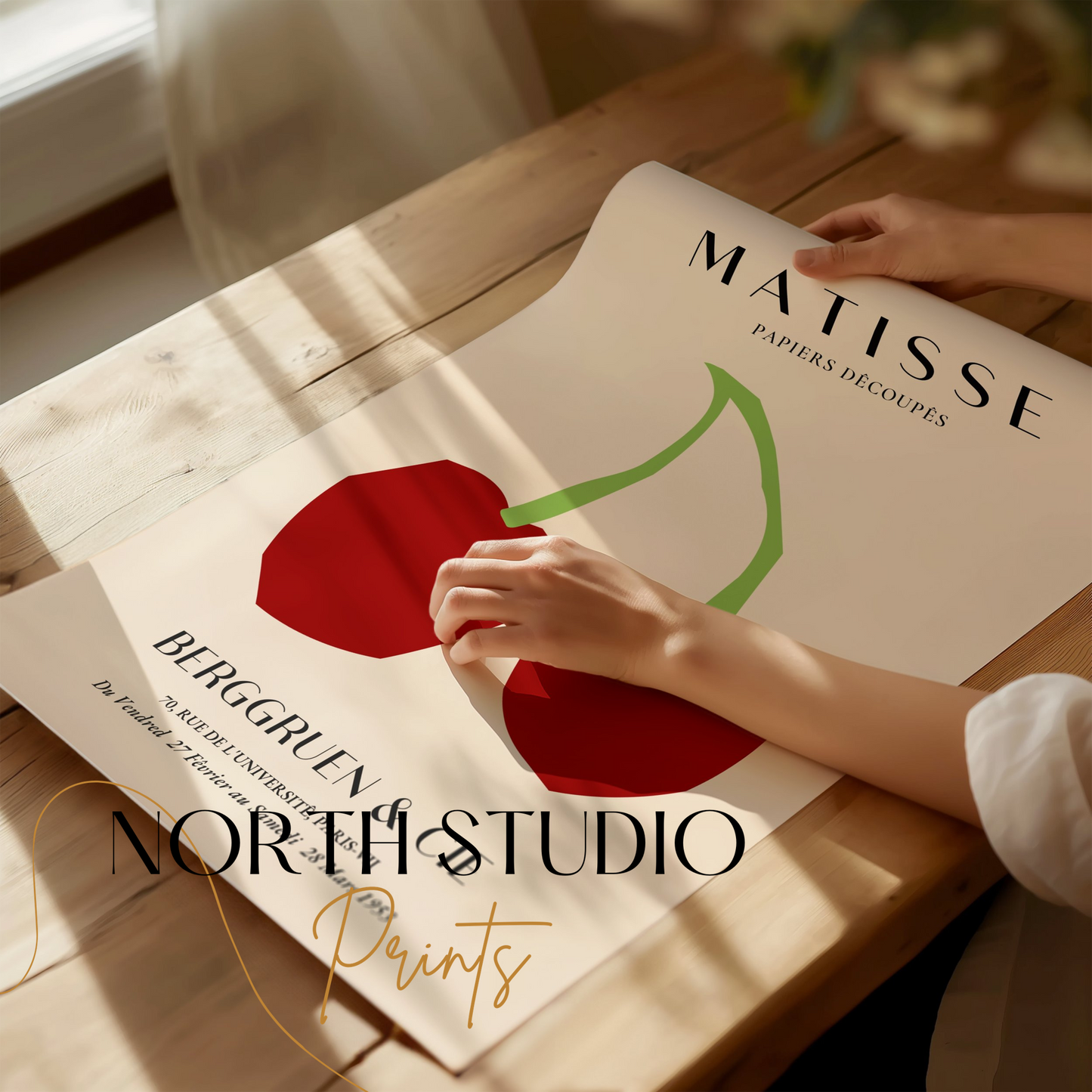 Close-up of Henri Matisse cherry art print poster being unrolled on a wooden table, showcasing minimalist design and vibrant colors.