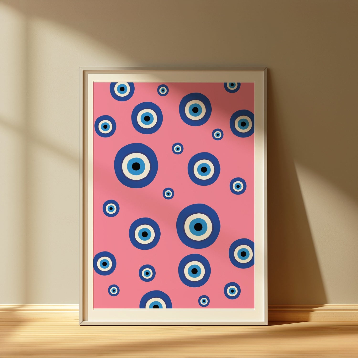 Abstract art poster with blue concentric circles on a pink background, framed and displayed in sunlight.