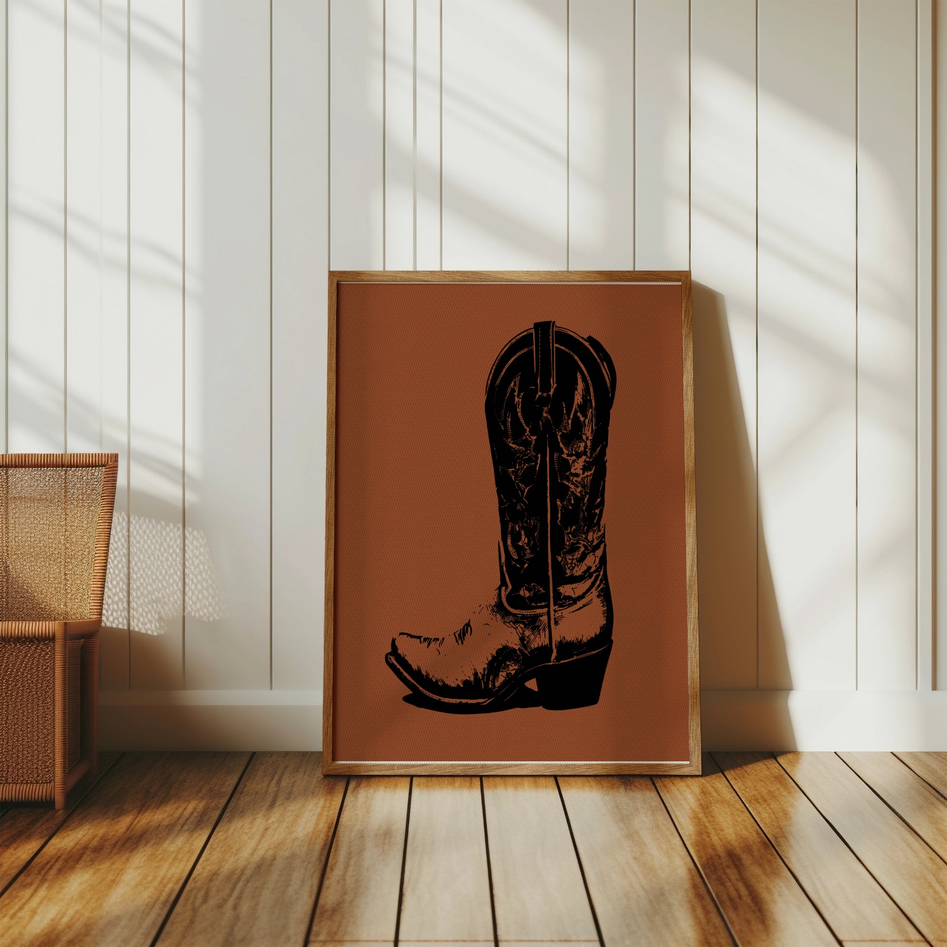 Framed artwork of a black cowboy boot silhouette on brown textured background.