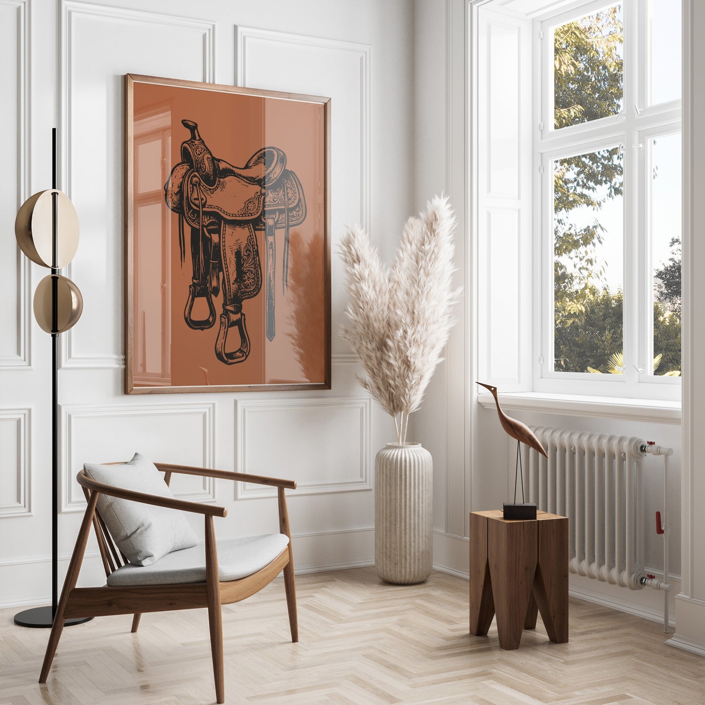 Framed illustration of a western saddle hangs above a wooden chair and pampas grass.