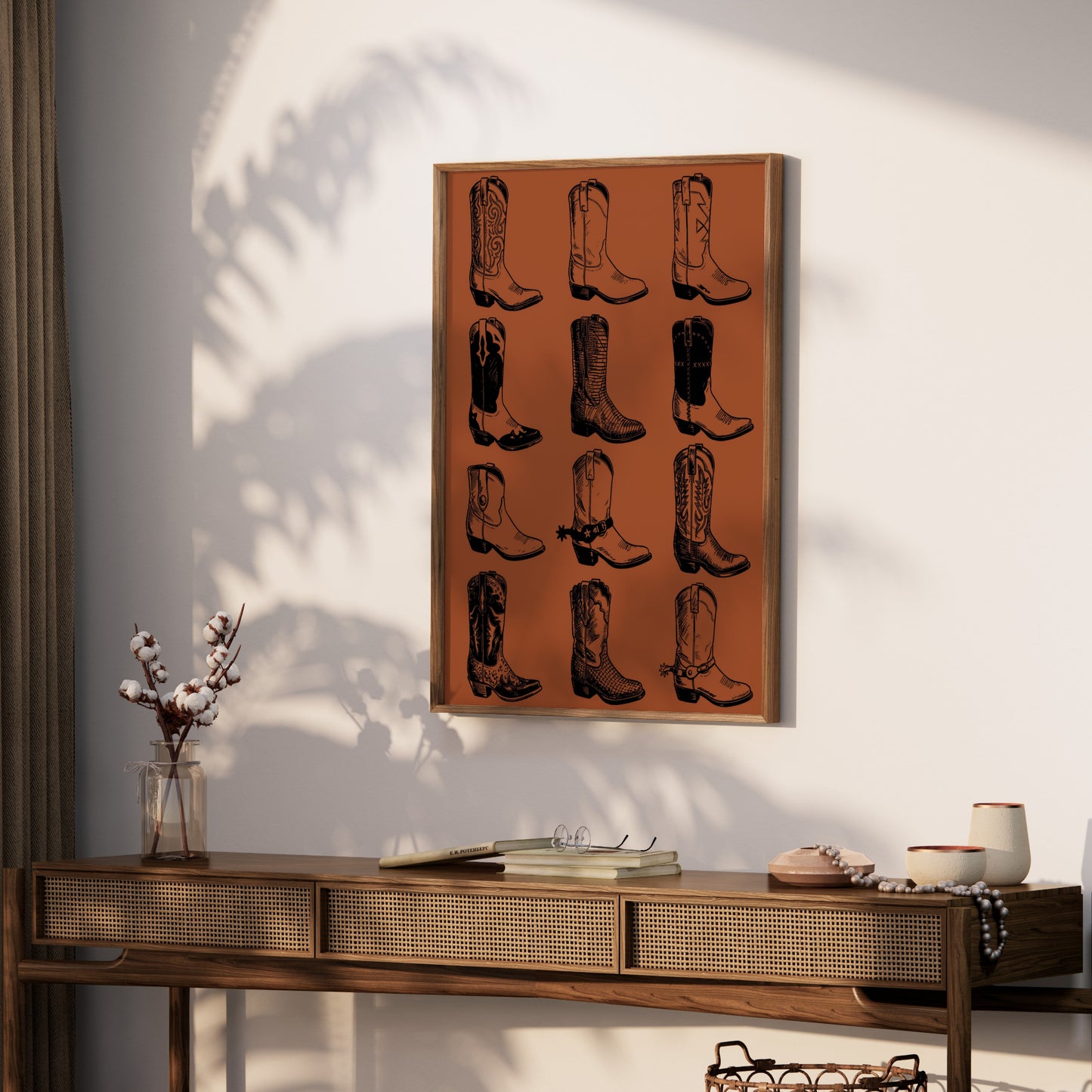 Framed artwork with a grid of 12 black and white cowboy boot illustrations on an orange background.