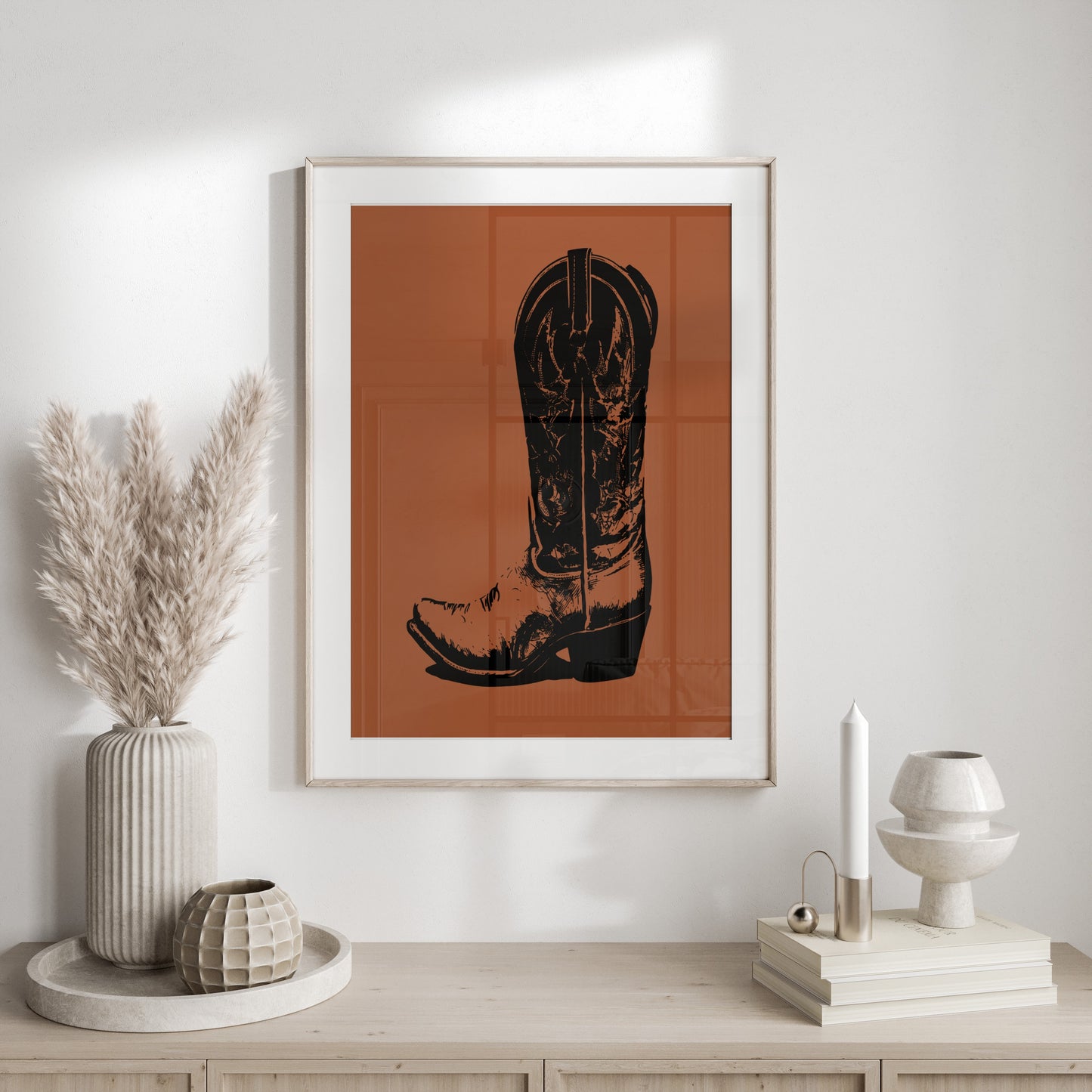Black cowboy boot silhouette on rust-colored background in a framed print.