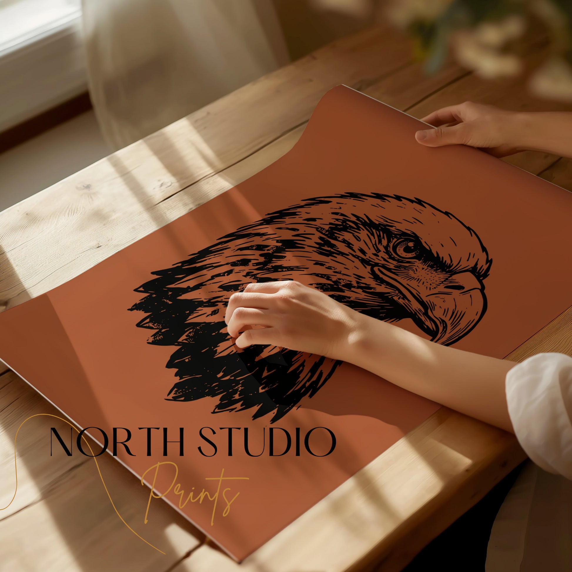 Black ink eagle head sketch on rust-colored paper, with "North Studio Prints" text.