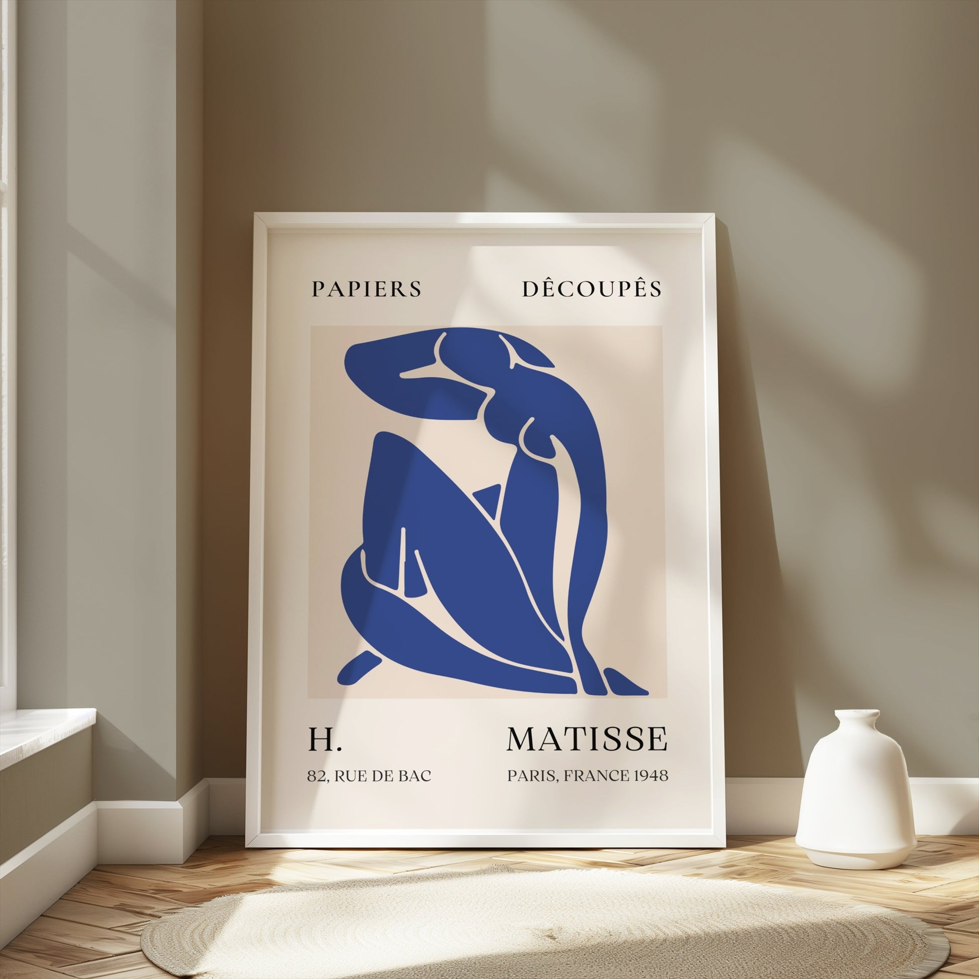 Framed Abstract Blue Figure Henri Matisse art poster leaning against a beige wall in a sunlit room, ideal for modern room decor.