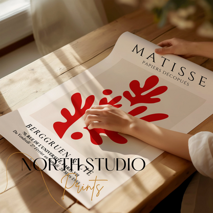 Close-up of Matisse Papiers Découpés poster with red abstract design, being unrolled on a wooden table, showcasing fine art details and premium quality.