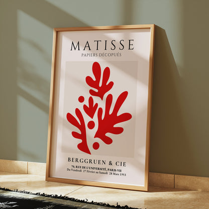 Matisse Papiers Découpés poster in a gold frame featuring bold red abstract design, leaning against a green wall on a tiled floor with soft lighting.