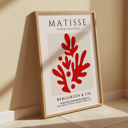Matisse Papiers Découpés poster with red abstract design, framed and leaning against a beige wall, styled with soft natural light in a minimalist space.