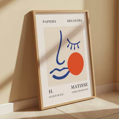 Framed Artistic Matisse Papercut Face Design Wall Art Poster leaning against a wall in a sunlit room, showcasing modern minimalistic home decor.