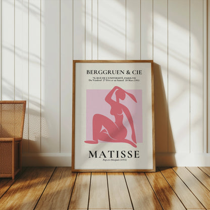 BERGGRUEN & CIE Matisse exhibition vintage poster in a wooden frame, leaning against a white paneled wall with sunlight streaming in.