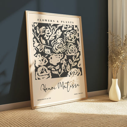 Framed Henri Matisse floral art print leaning against a dark green wall, showcasing abstract black and white botanical design for modern interiors.