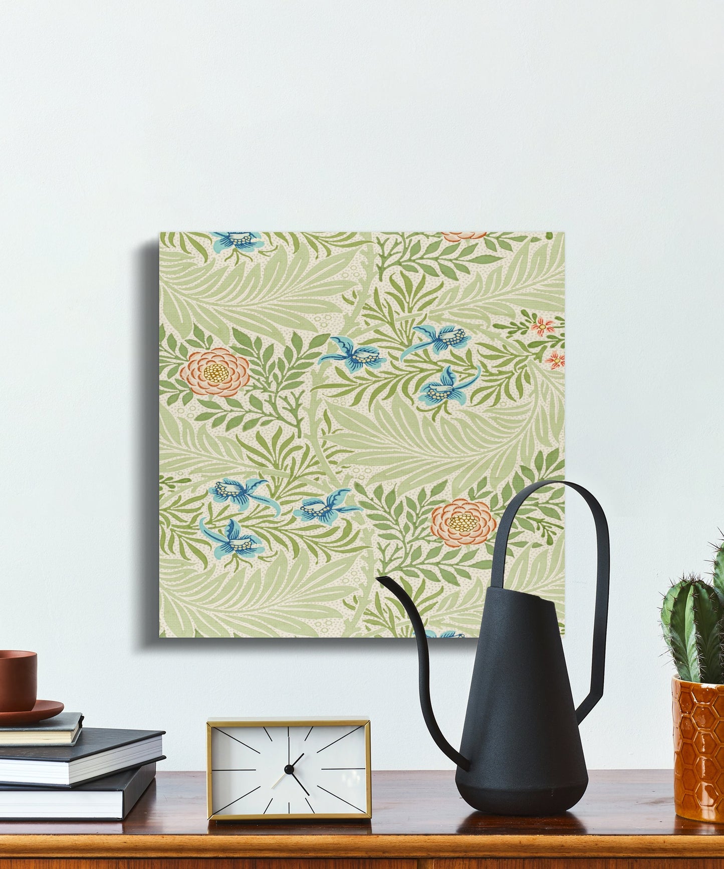 William Morris floral canvas wrap with botanical art, styled on a desk with books, a clock, and a black watering can for a classic touch.
