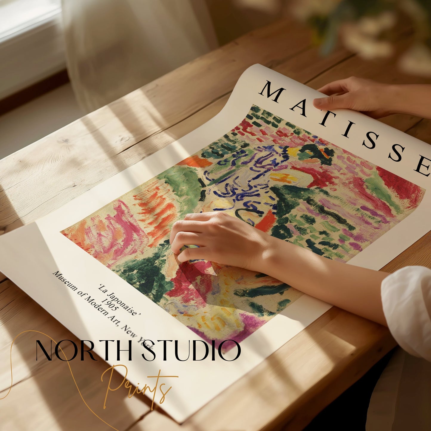 Unframed Matisse La Japonaise poster being handled on a wooden table. A high-quality art print perfect for framing and display.