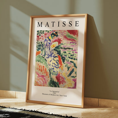 Framed Matisse La Japonaise poster resting against a green wall with tiled flooring. A colorful and historic art print for home decor.