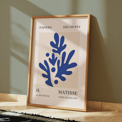 Framed Matisse-style Parisian art print with blue abstract botanical design, leaning against a green wall, perfect for stylish interiors.