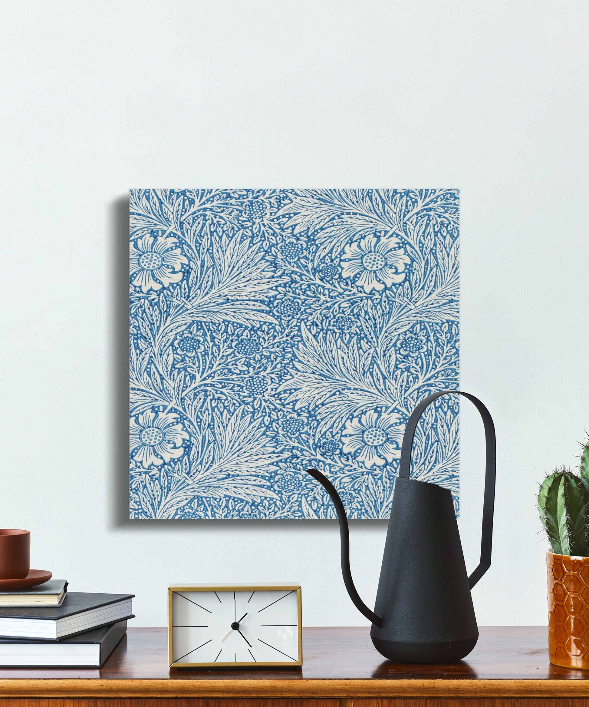 William Morris floral canvas wrap on a white wall, styled with books, a clock, and decor items for a classic and sophisticated look.