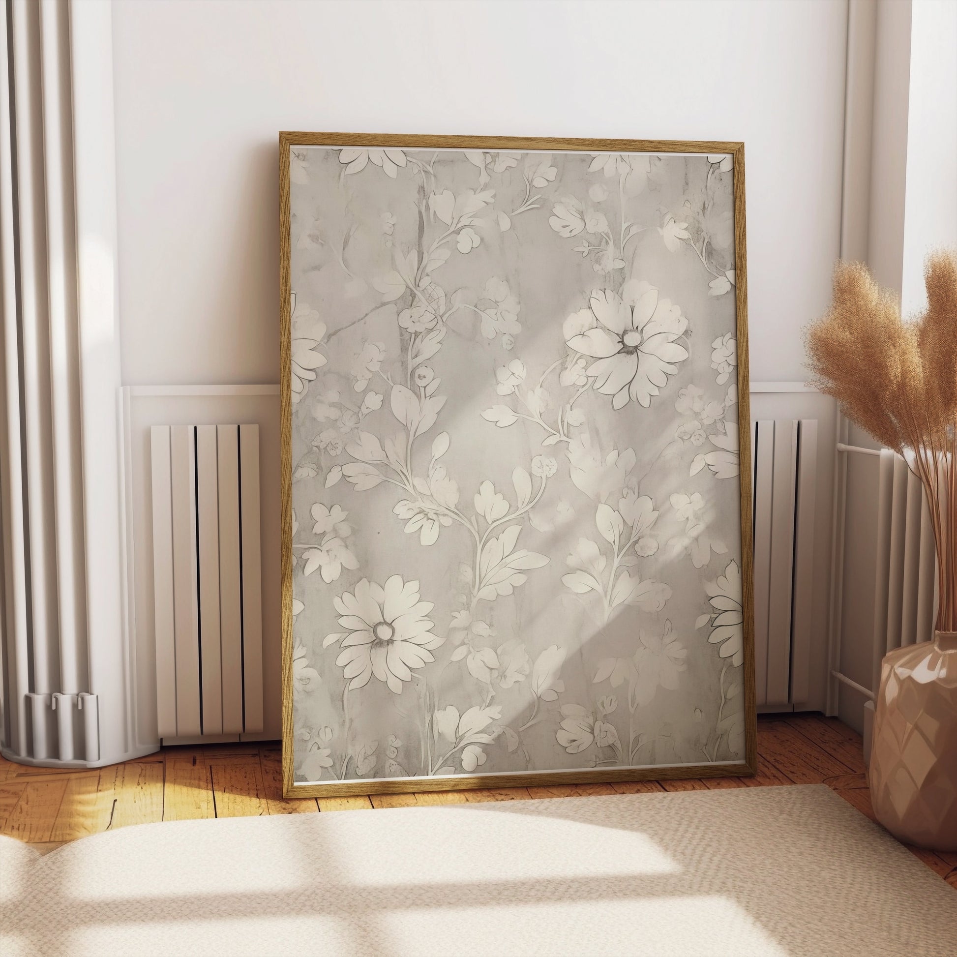 Floral art print with white flowers in a gold frame, leaning against a wall in a sunlit room with minimalist decor.
