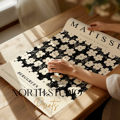 Close-up of a Matisse Flowers & Plants poster being unrolled on a wooden table, showcasing its intricate floral design and vintage typography.