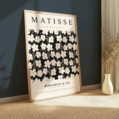 Framed Matisse Flowers & Plants poster leaning against a dark wall, styled with a vase of dried plants on a textured carpet.