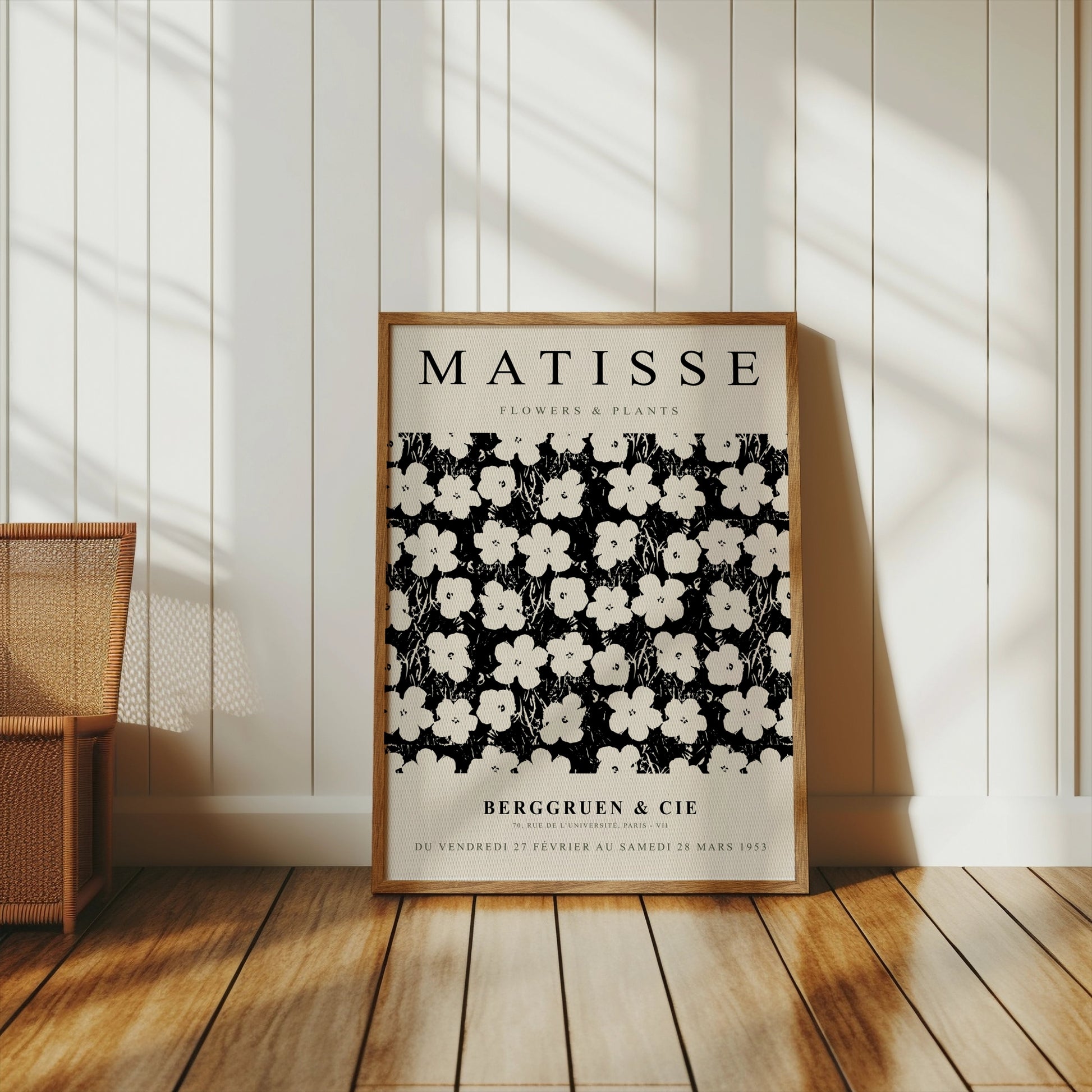 Framed Matisse Flowers & Plants poster leaning against a white paneled wall, styled with a wicker chair and natural sunlight.