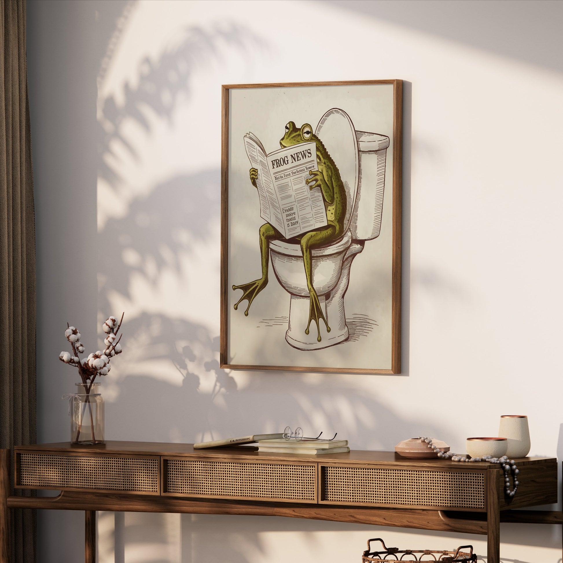 Frog reading newspaper on toilet poster framed and hung above a wooden console table, creating a playful and unique decor piece.