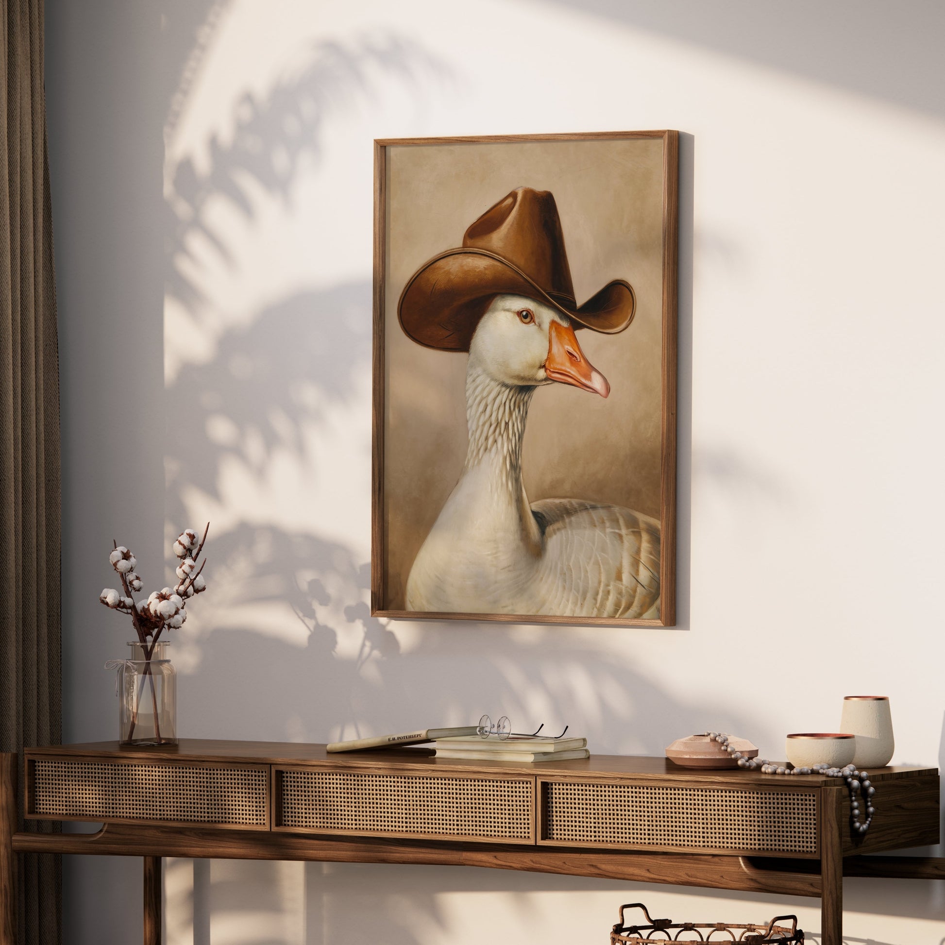 Goose wearing cowboy hat art print mounted on a wall above a wooden console table, adding a touch of humor and charm to the space.