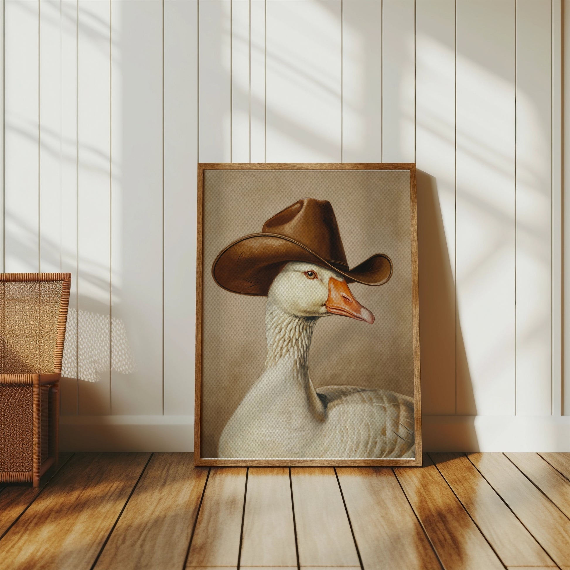 Goose wearing cowboy hat art print leaning against a white paneled wall, blending vintage style with whimsical decor in a rustic setting.