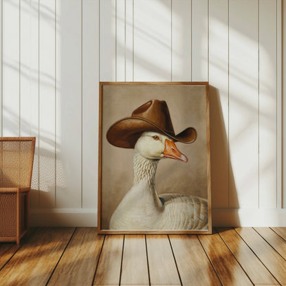 Goose wearing cowboy hat art print leaning against a white paneled wall, blending vintage style with whimsical decor in a rustic setting.