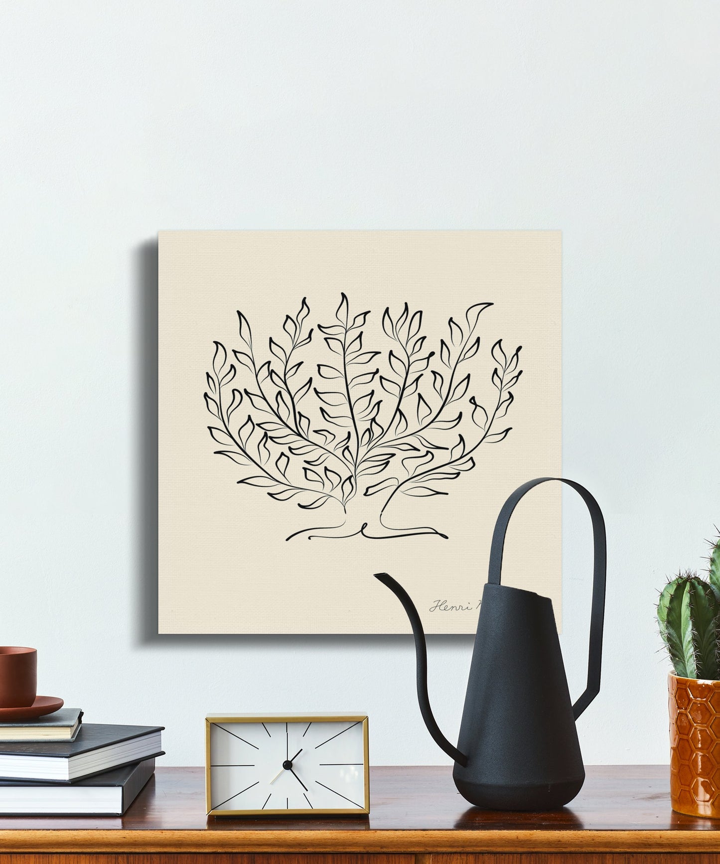 Henri Matisse-inspired plant illustration canvas placed on a wooden desk with books, a clock, and a watering can for chic decor.