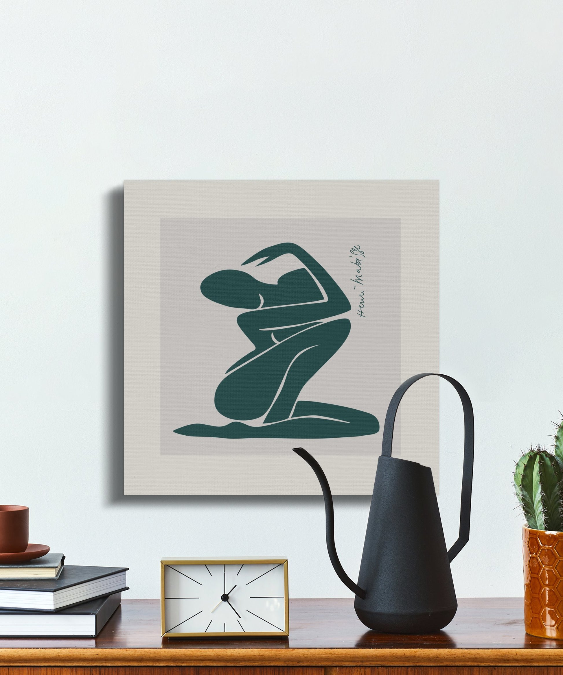 Abstract teal figure canvas wrap styled on a desk with books and decor, perfect for adding artistic flair to a workspace.