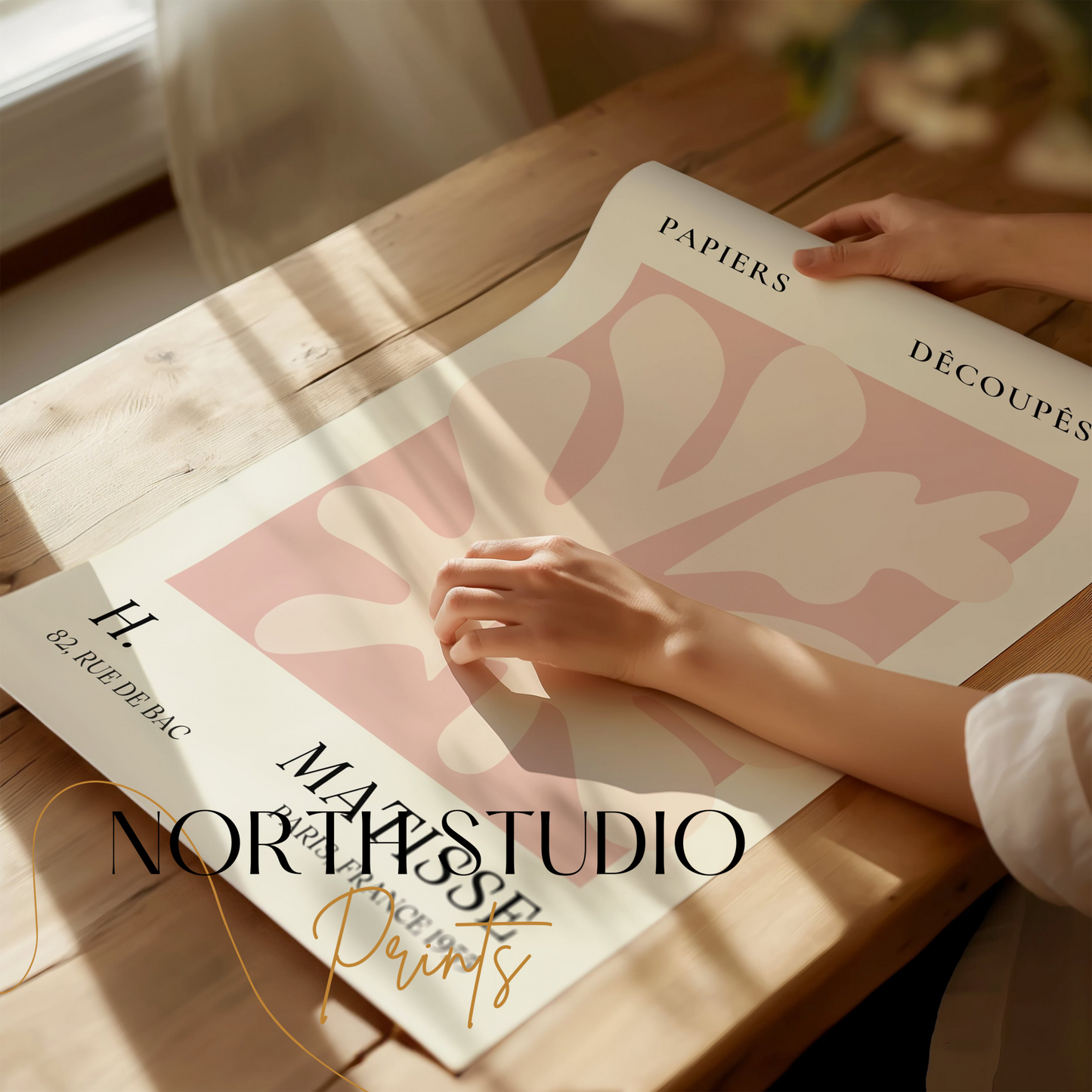 Henri Matisse inspired Papiers Decoupes art print poster being unrolled on a wooden table, showcasing its abstract design and vintage typography.