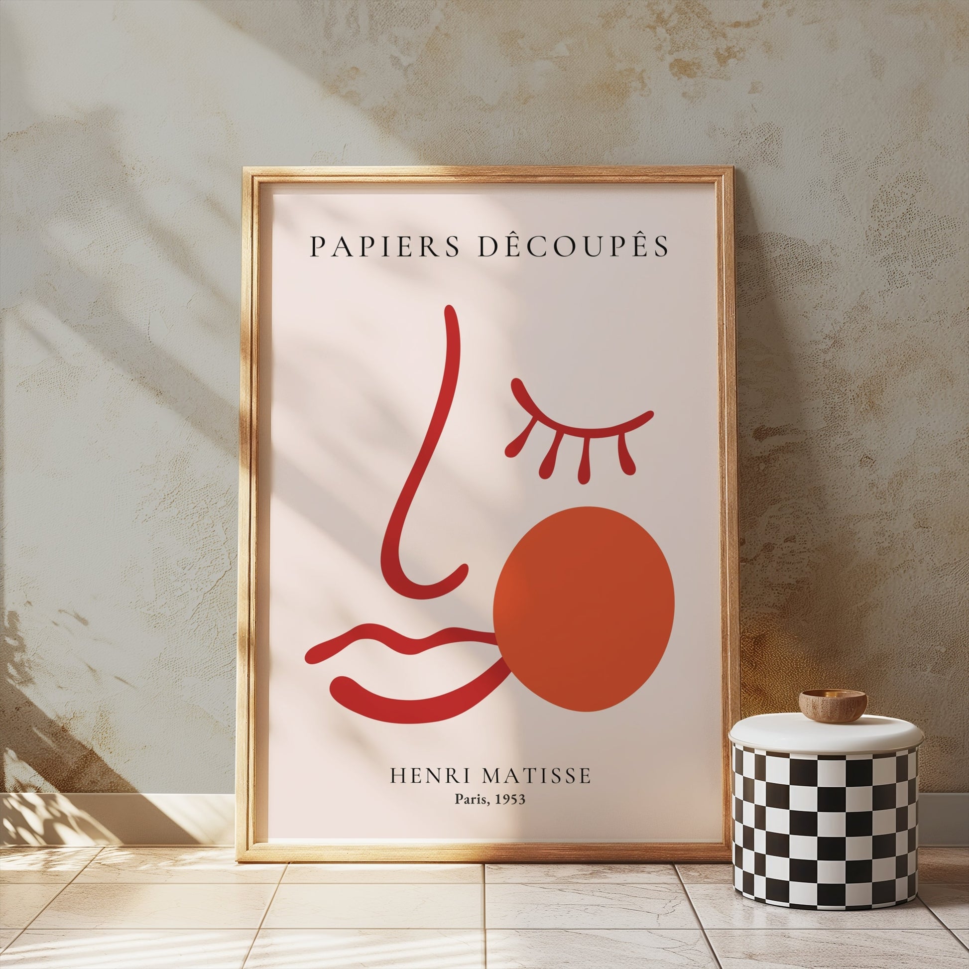 Henri Matisse Papiers Decoupes Paris 1953 art poster in a wooden frame, placed on a textured wall with a checkered decor piece nearby.