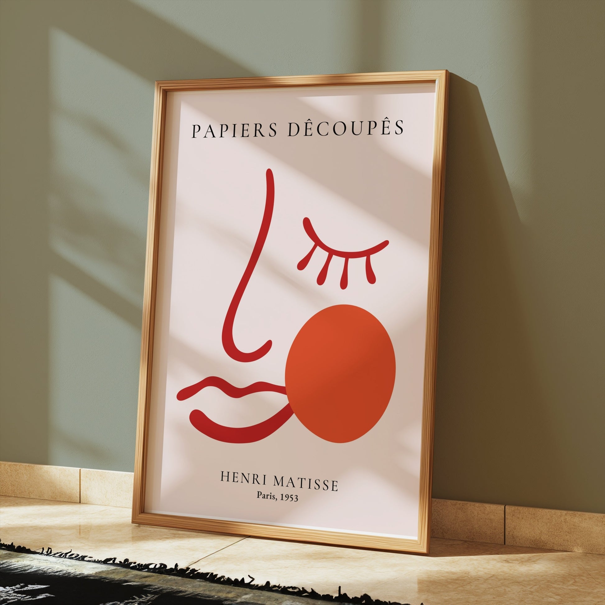 Henri Matisse Papiers Decoupes Paris 1953 art poster in a wooden frame, leaning against a green wall with sunlight streaming in.