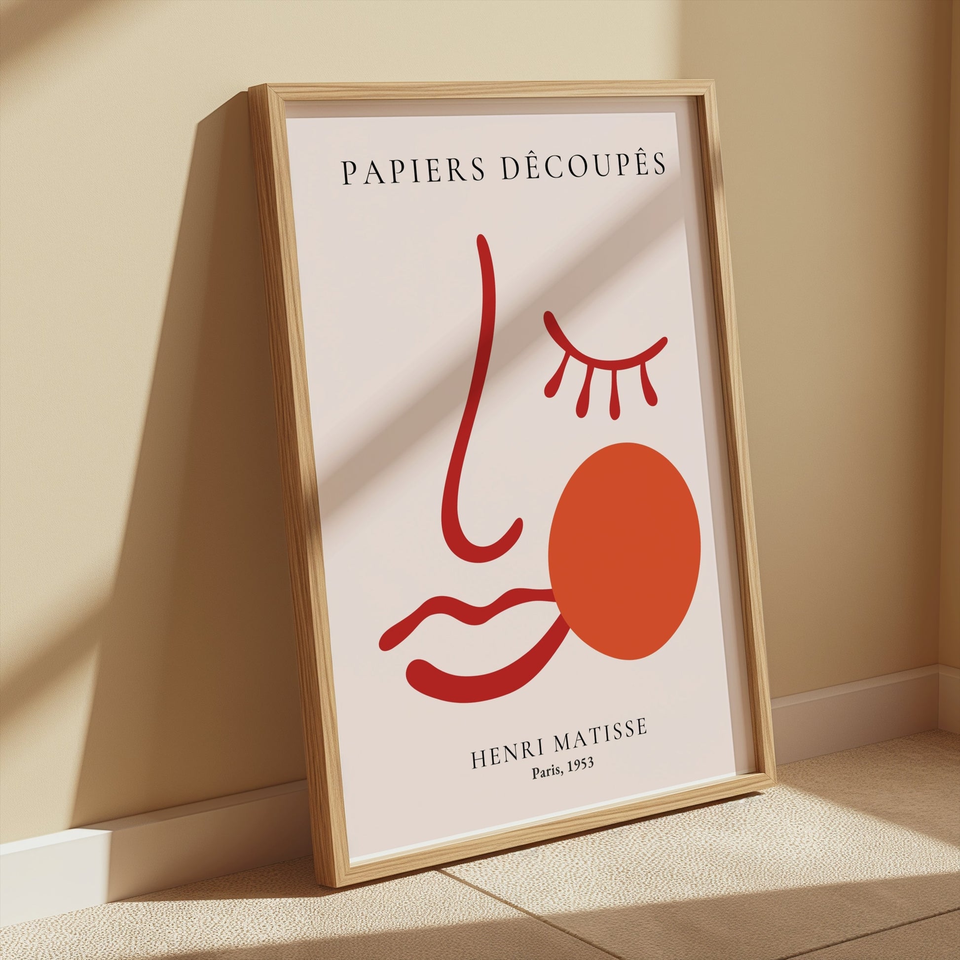 Henri Matisse Papiers Decoupes Paris 1953 art poster in a wooden frame, leaning against a beige wall with soft sunlight and minimalist decor.