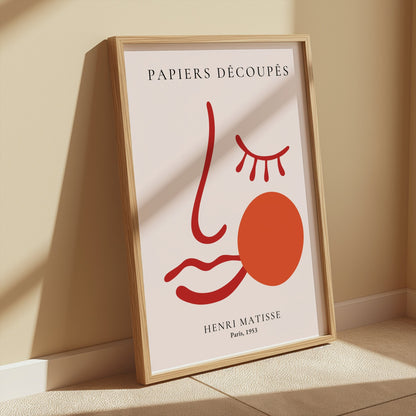 Henri Matisse Papiers Decoupes Paris 1953 art poster in a wooden frame, leaning against a beige wall with soft sunlight and minimalist decor.