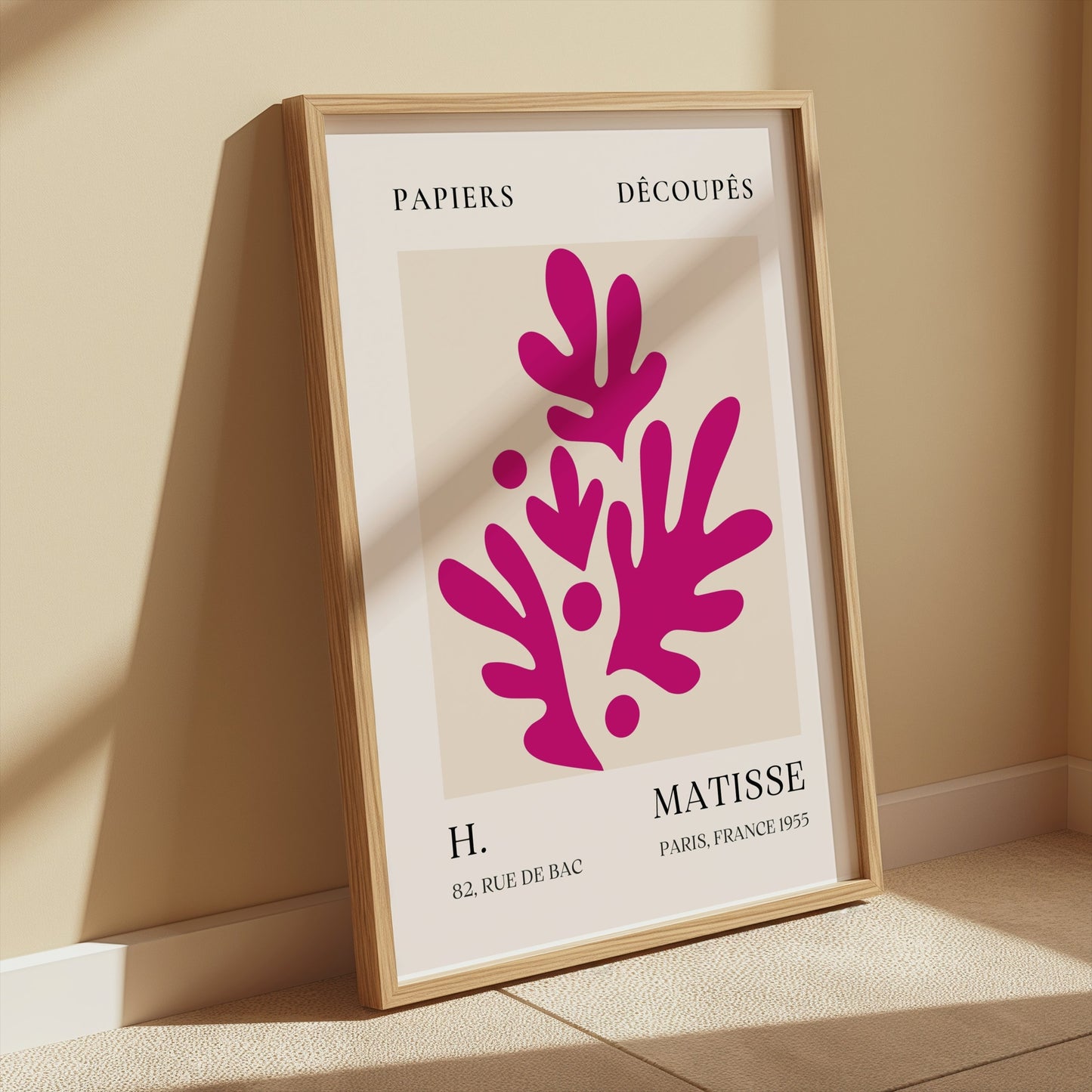 Henri Matisse Paris France 1955 Papiers Découpés poster in a wooden frame leaning against a beige wall, styled with sunlight and minimalist decor.