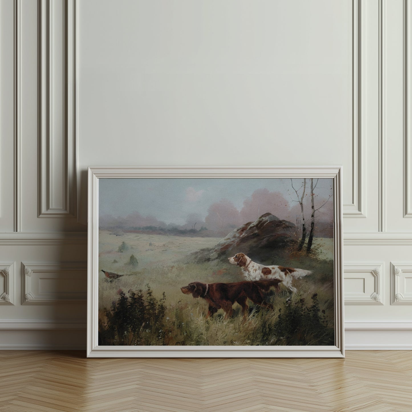 Hunting dogs in misty forest landscape poster in a white frame, leaning against an ornate wall in a classic interior.
