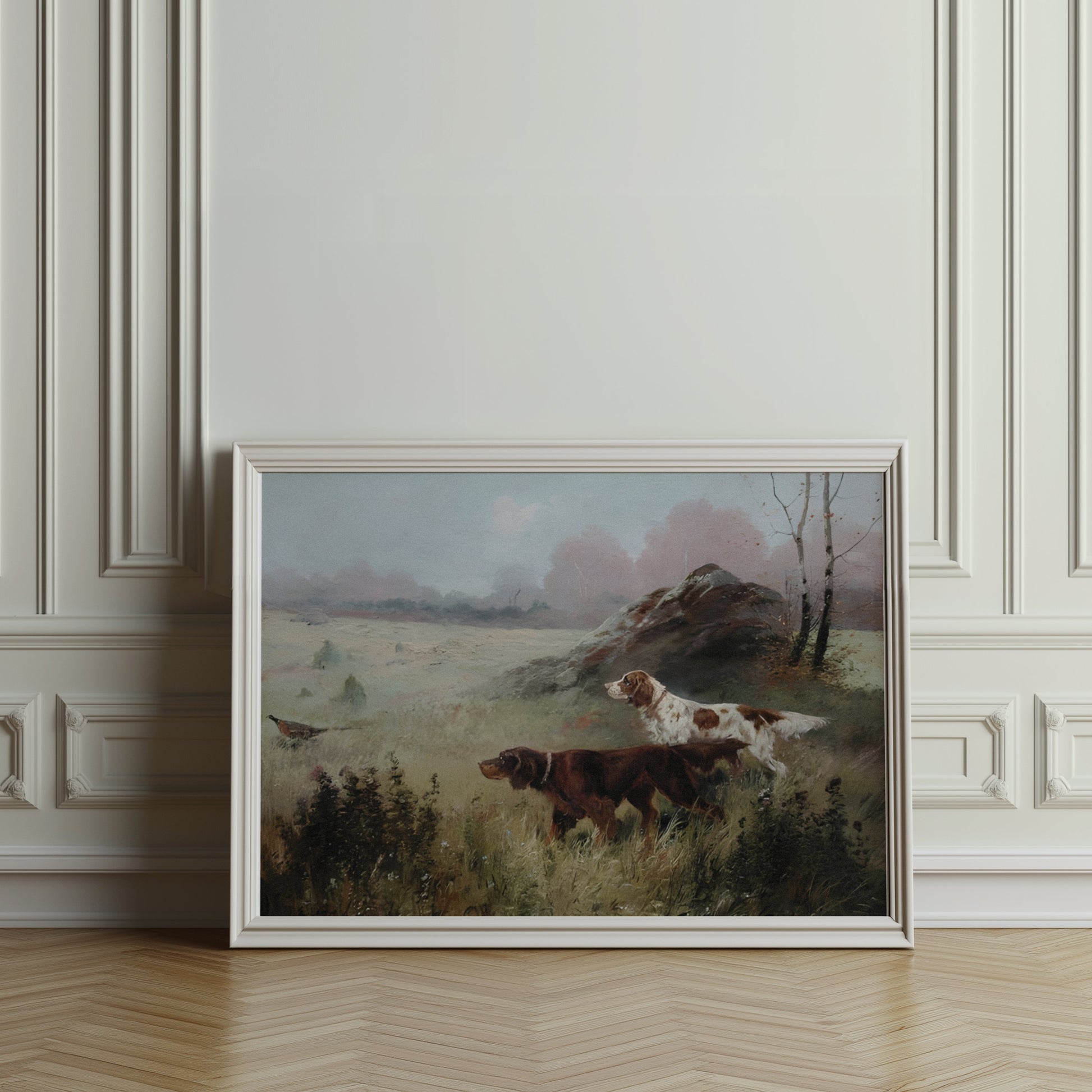 Hunting dogs in misty forest landscape poster in a white frame, leaning against an ornate wall in a classic interior.