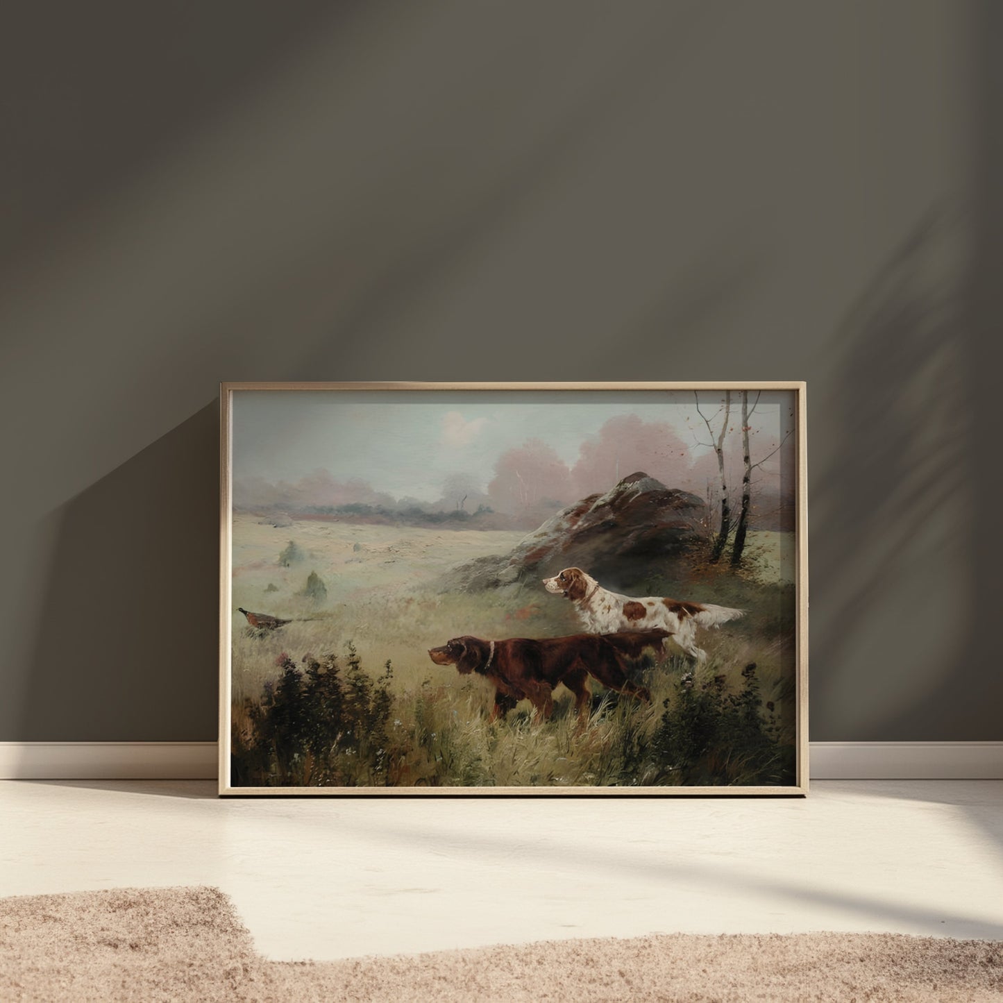 Framed hunting dogs in misty forest landscape poster placed on the floor against a dark wall with soft lighting.