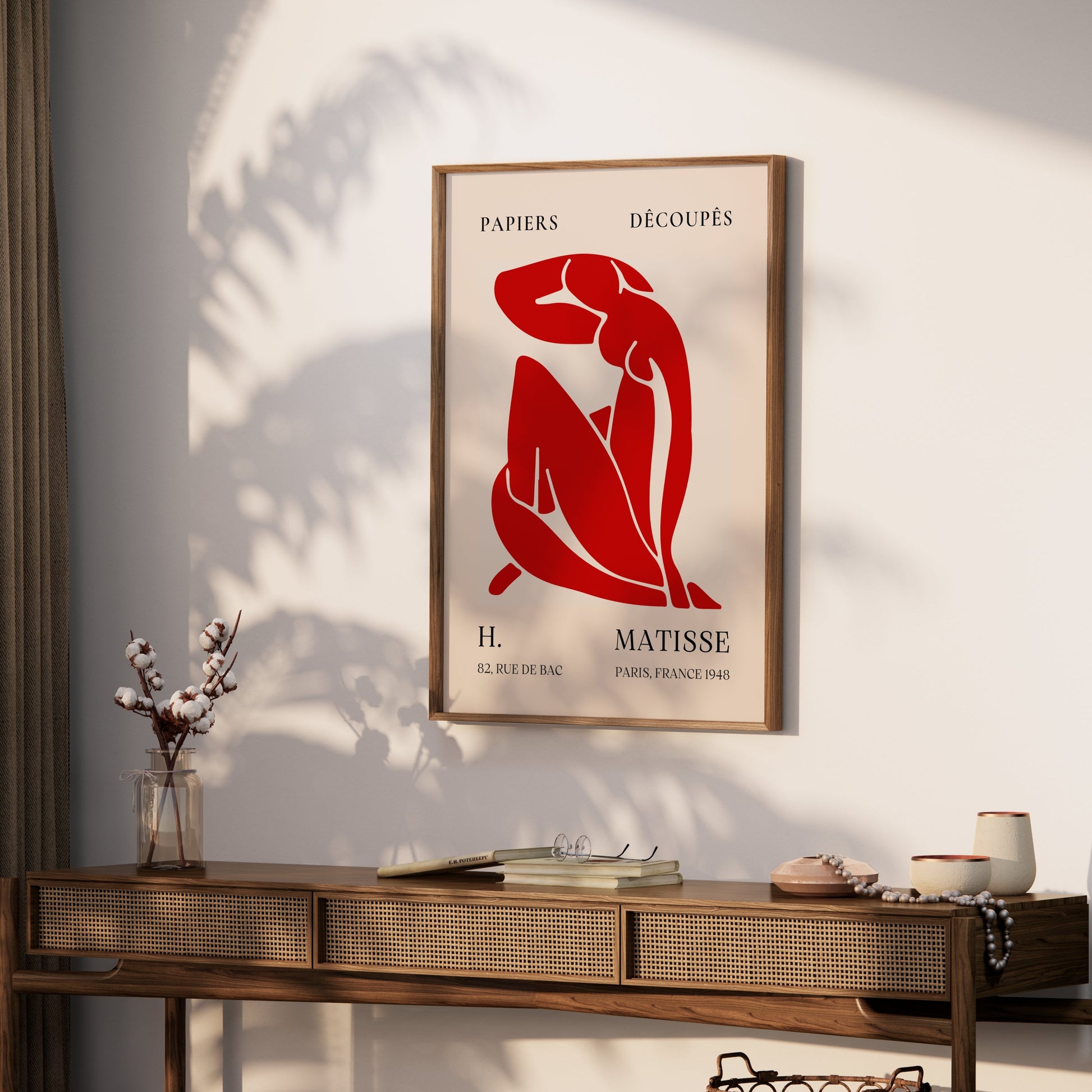 Framed H. Matisse 1948 Papiers Découpés poster displayed on a wooden console table with decorative accents, adding artistic charm to the room.