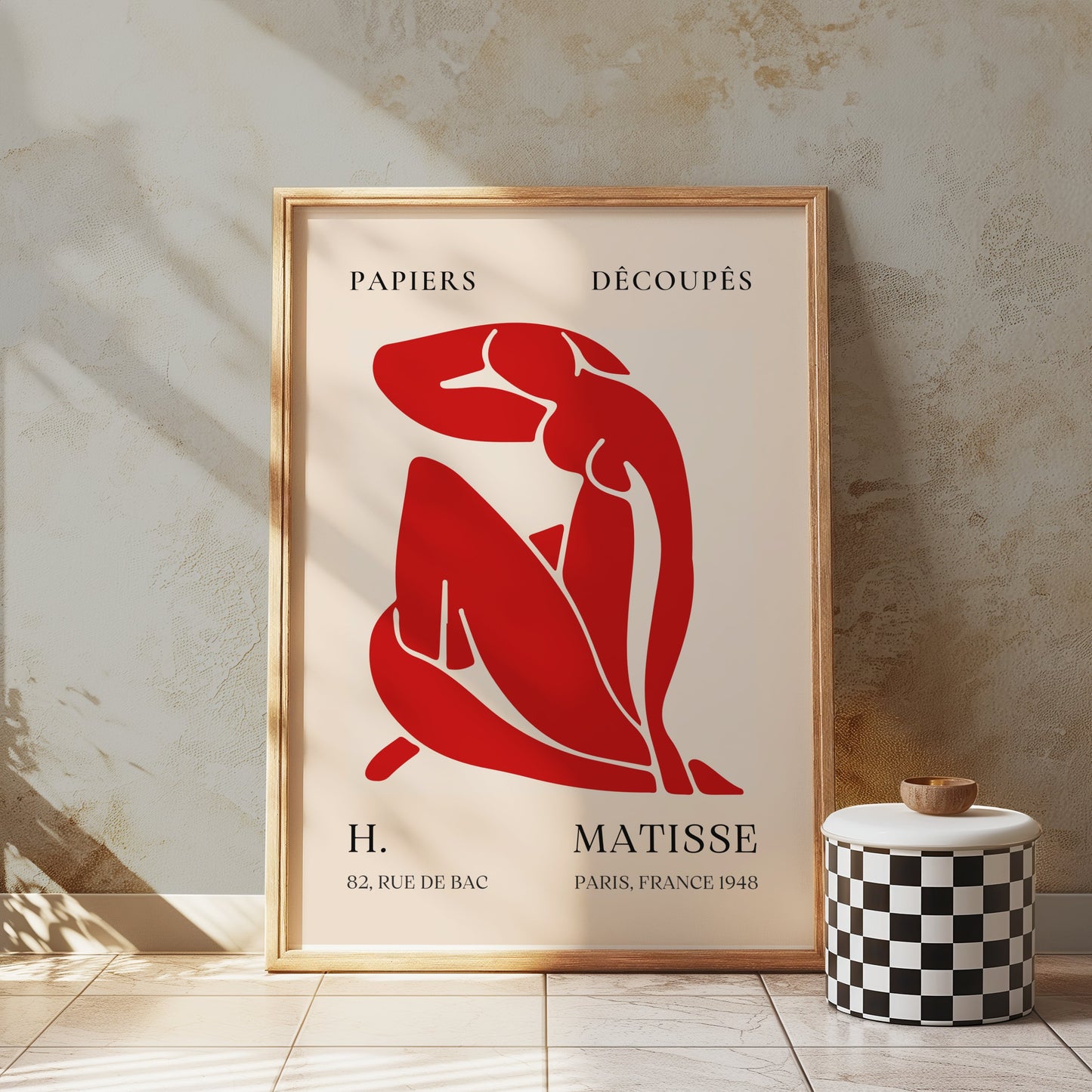 H. Matisse 1948 Papiers Découpés poster in a rustic wooden frame, displayed in a textured space with a checkered stool, adding artistic flair.
