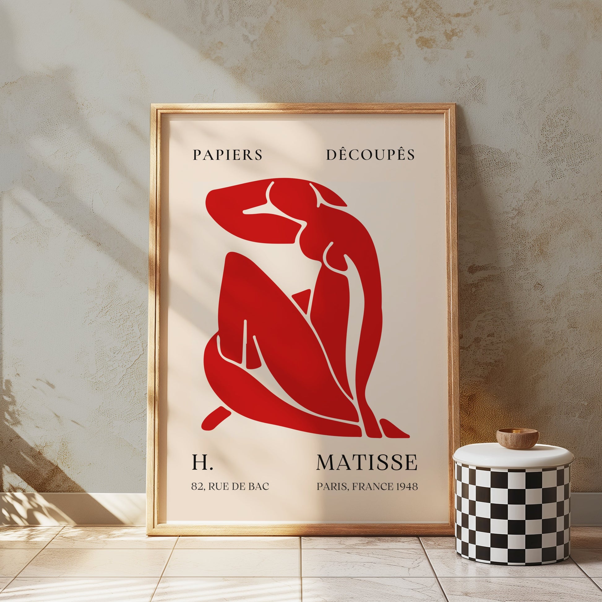 H. Matisse 1948 Papiers Découpés poster in a rustic wooden frame, displayed in a textured space with a checkered stool, adding artistic flair.