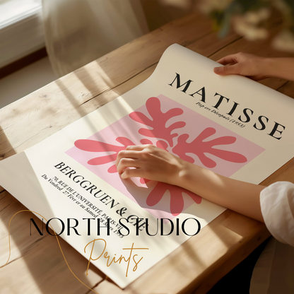 Unframed Matisse Art Exhibition Paris 1953 poster with pink abstract design, being unrolled on a wooden table.