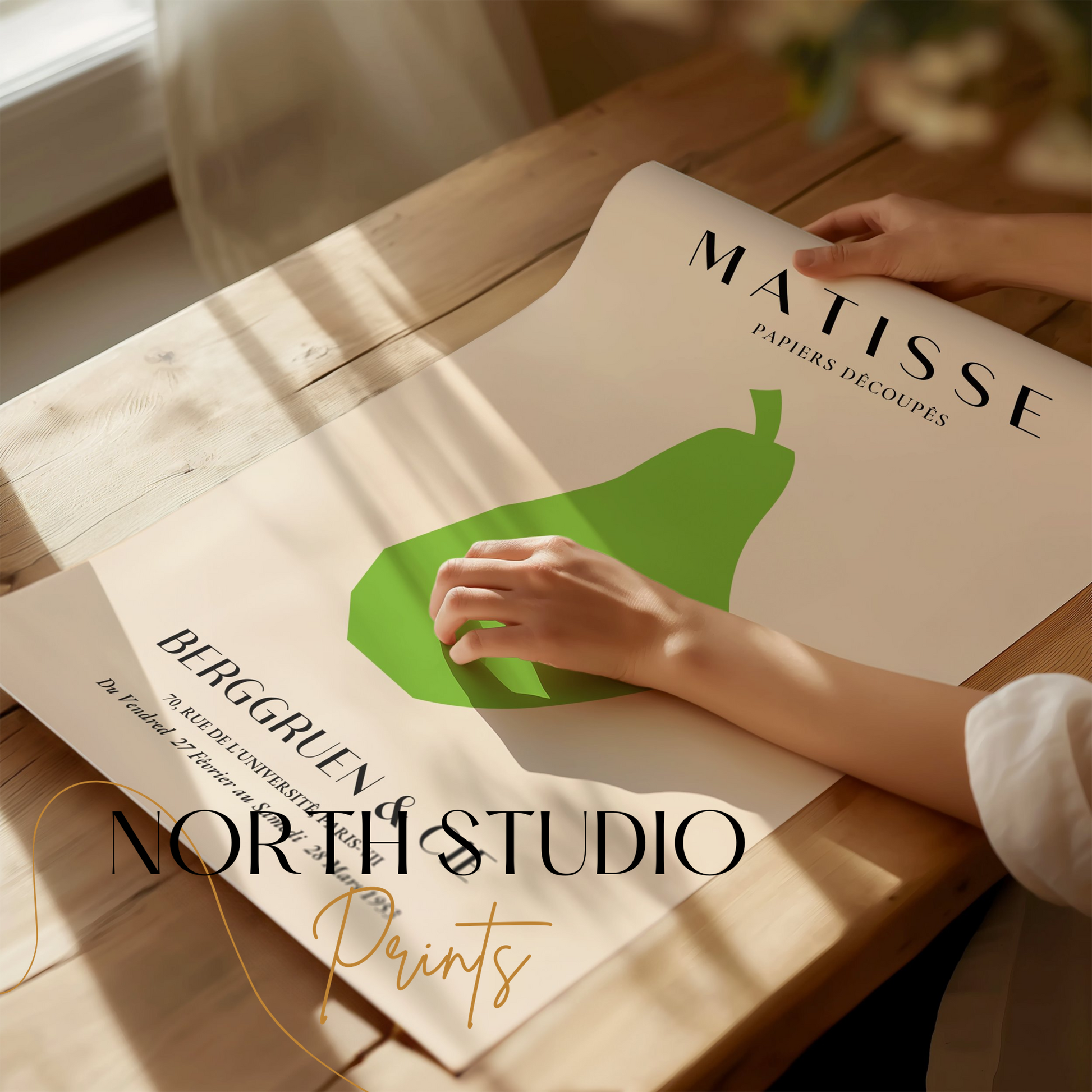 Hands unrolling a Matisse green pear art print on a wooden table, showcasing its minimalist design for home decor.