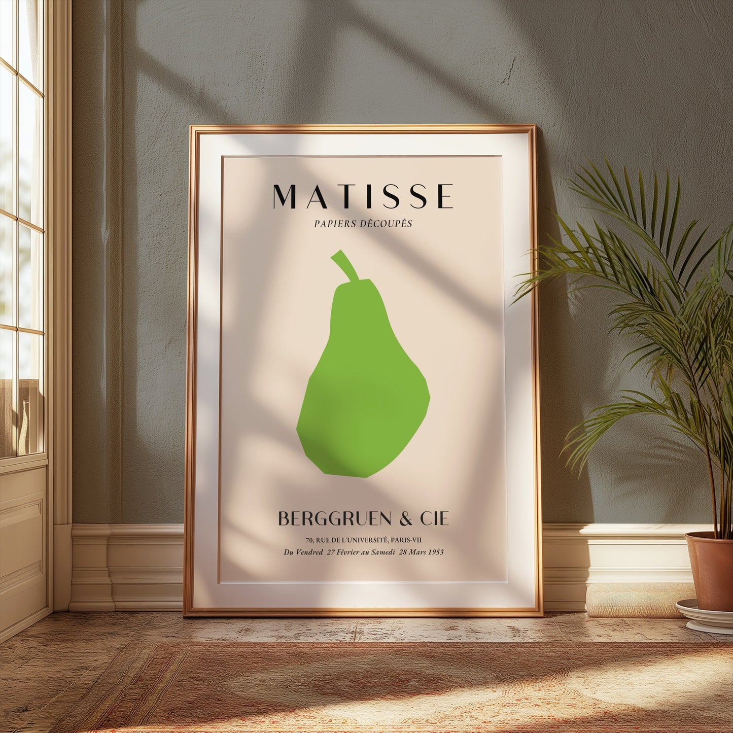 Framed Matisse green pear art print leaning against a wall in a sunlit room with plants, enhancing modern home decor.