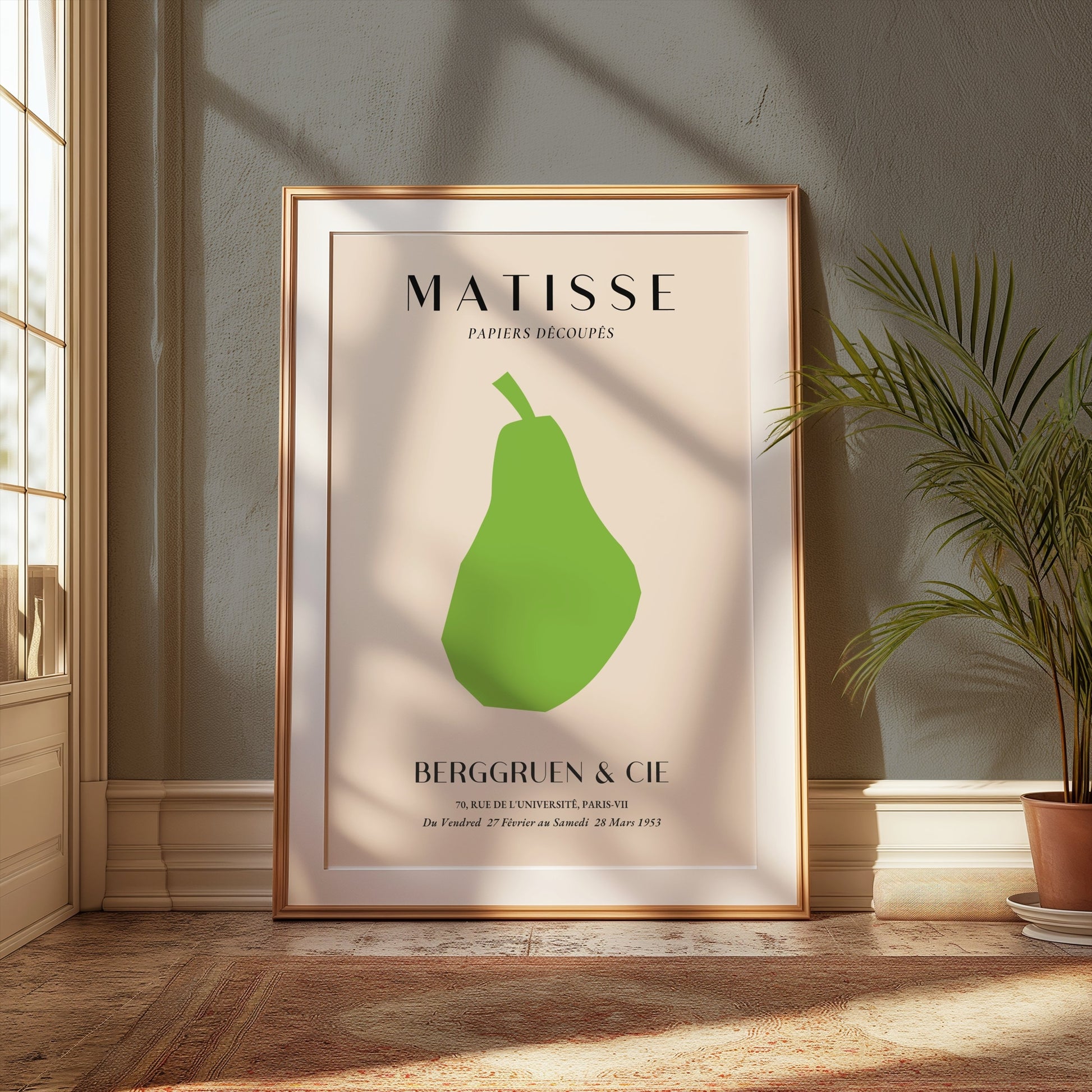 Framed Matisse green pear art print leaning against a wall in a sunlit room with plants, enhancing modern home decor.