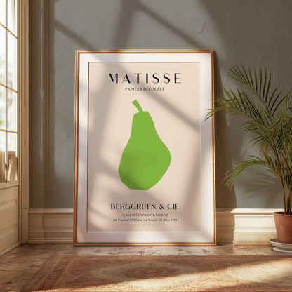 Framed Matisse green pear art print leaning against a wall in a sunlit room with plants, enhancing modern home decor.