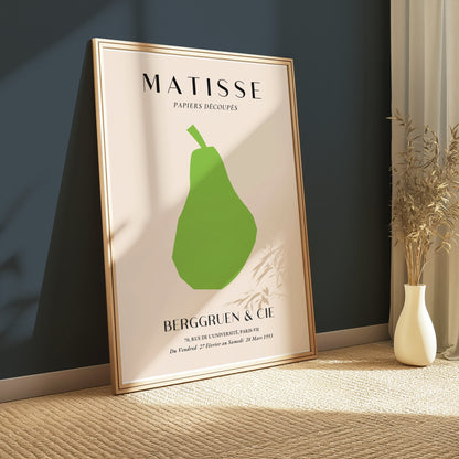Matisse green pear poster in a wooden frame, propped against a dark teal wall with natural light and minimalist decor.