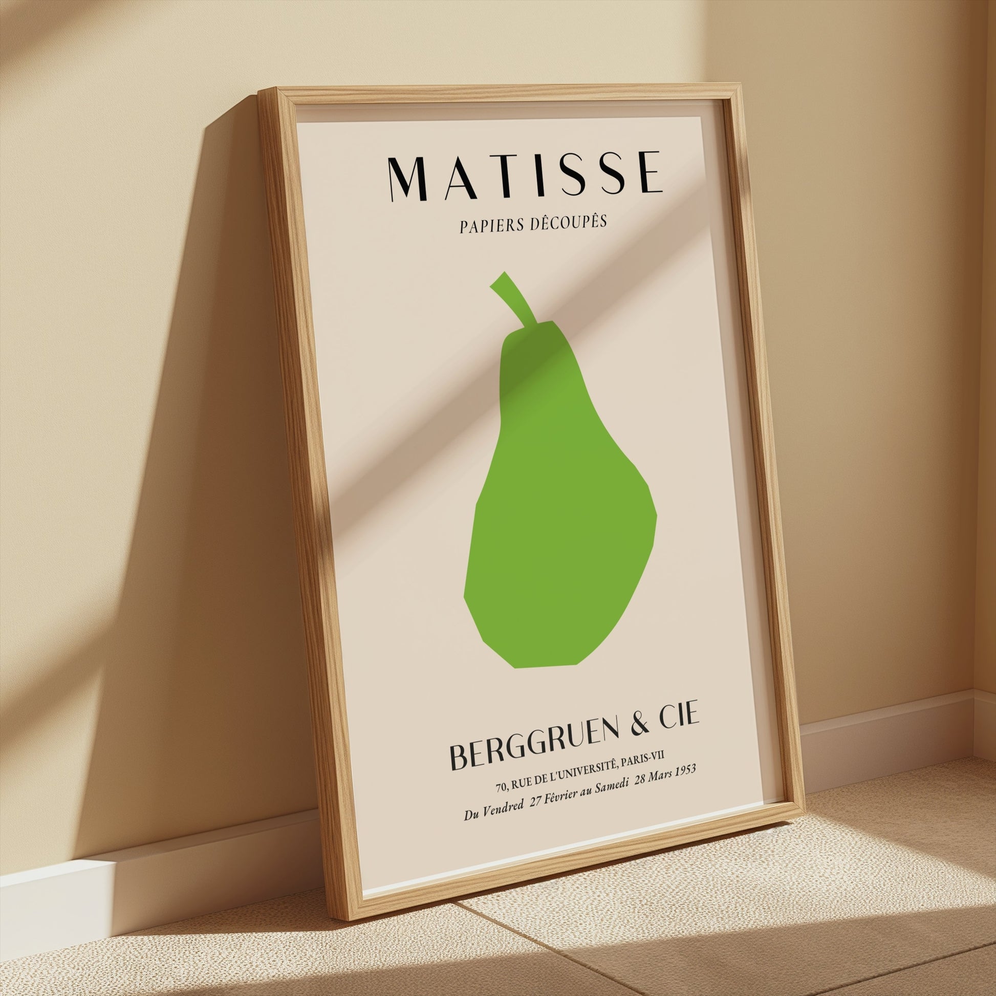 Framed Matisse green pear art print leaning against a beige wall with warm sunlight, perfect for minimalist wall decor.