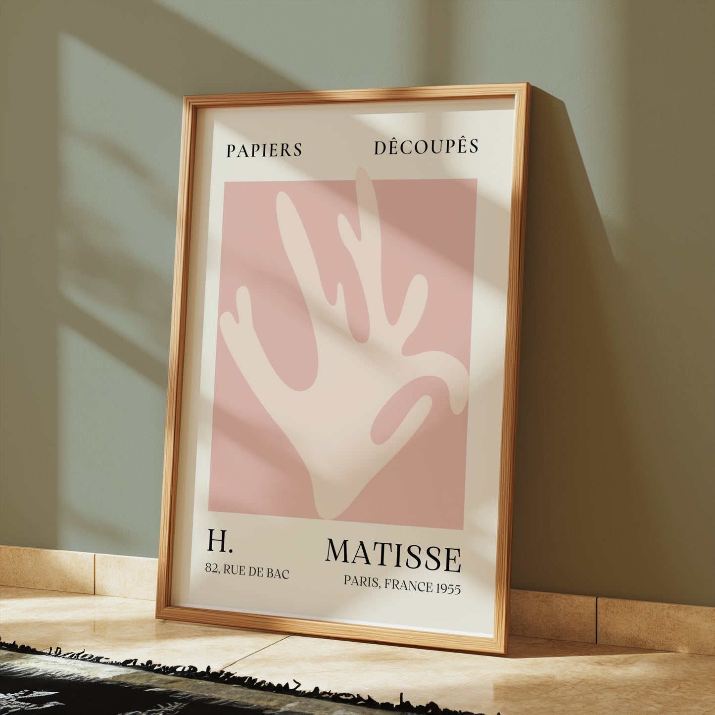 Matisse Coral Hand Inspired Paris Art Poster in a wooden frame, placed on a tiled floor with soft sunlight for a modern home decor vibe.